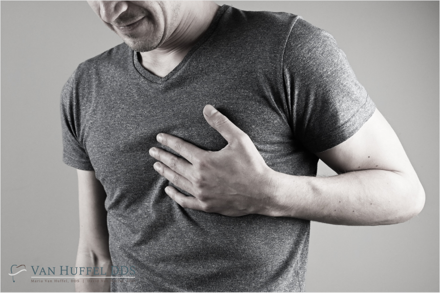 Black and white illustration of a man clutching his chest, with a distressed expression, symbolizing chest pain or discomfort.